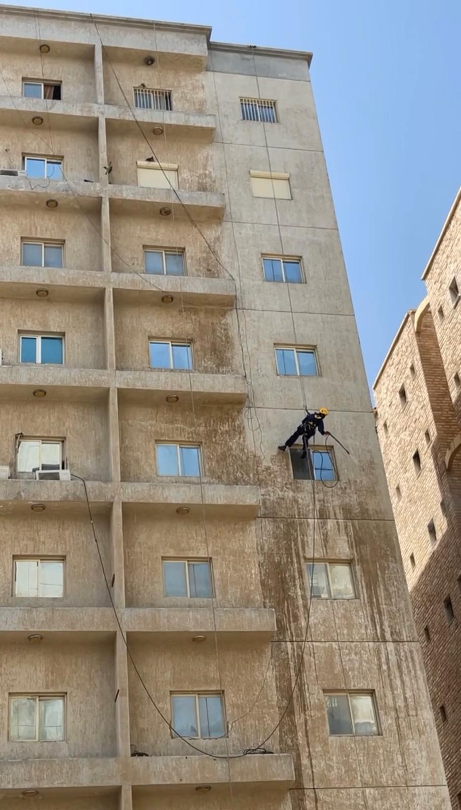فني حبال يعمل على واجهة مبنى في الكويت